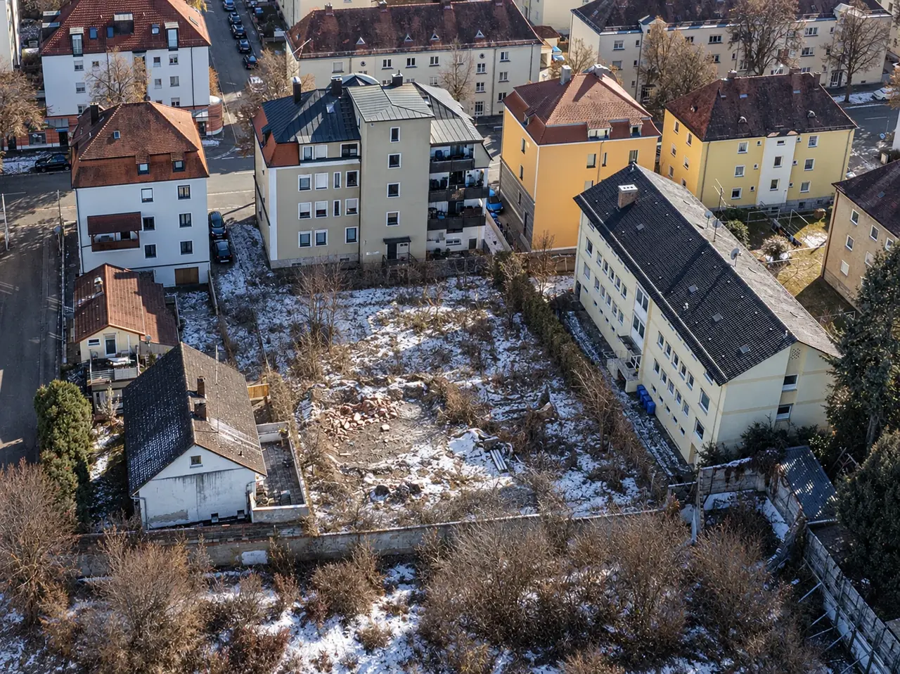 Luftbild des Ausgangszustands: brachliegendes Grundstück zwischen mehrgeschossigen Wohnhäusern