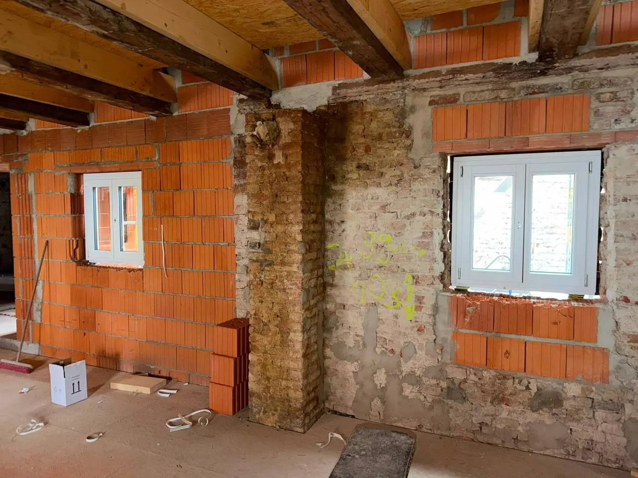 Rohbauraum mit neuen Fenstern im historischen Mauerwerk und neuen Ziegelwänden
