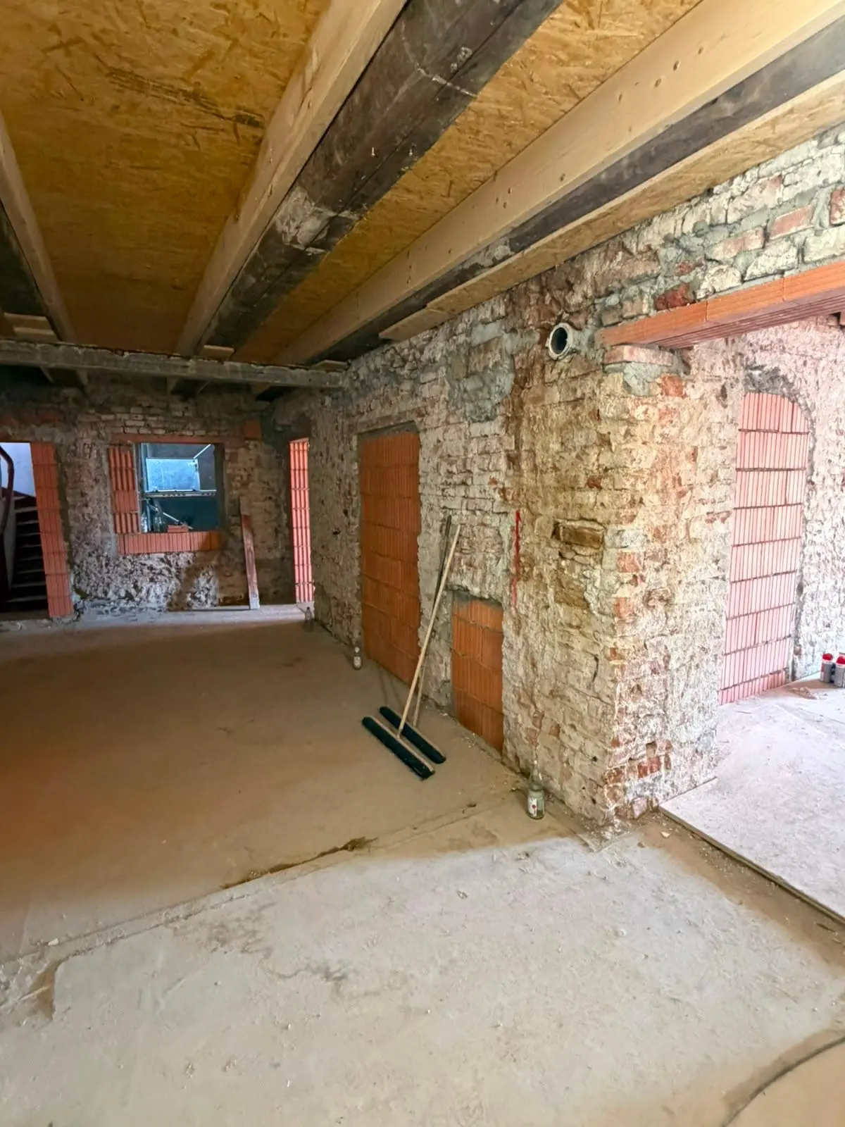 Dachgeschoss im Rohbau mit Holzbalken und freigelegten Wänden