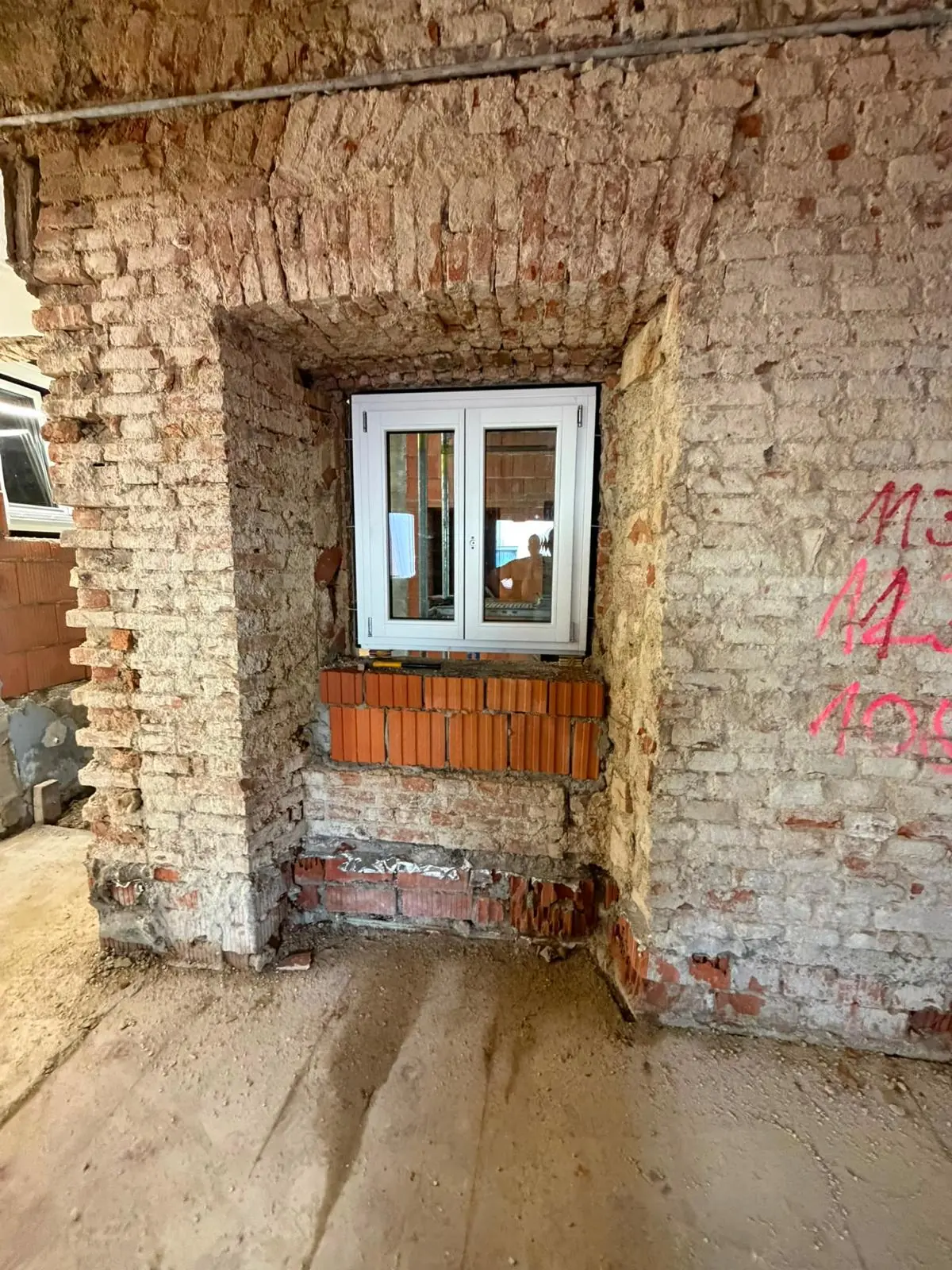 Neues Fenster in einer Öffnung des historischen Mauerwerks, markiert für die weiteren Arbeiten